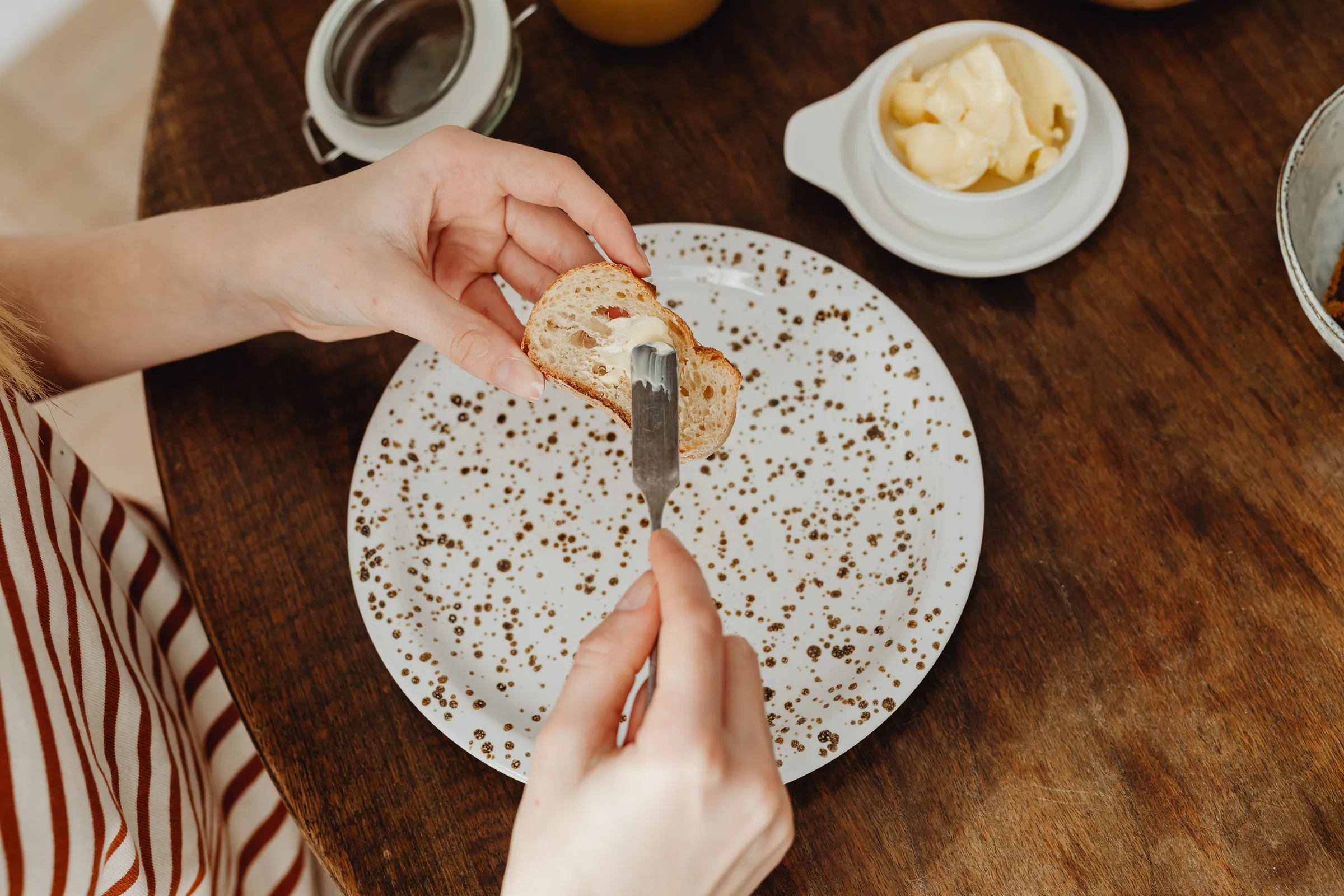 Nahaufnahme einer Person, die Butter auf eine Scheibe Brot streicht